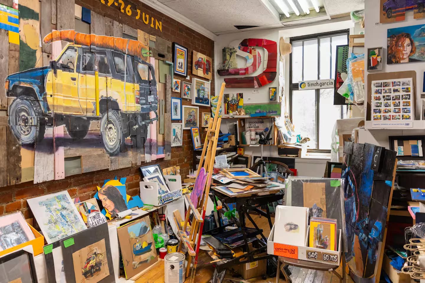 Atelier d'artiste rempli de toiles, chevalet et grande peinture de camion, chez un artiste représenté par L'Original