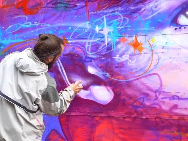 Artist spray painting a mural
