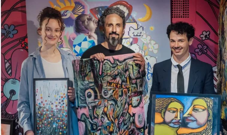 Deux artistes représentés par la galerie tiennent leurs œuvres aux côtés de Dorian Verdier, devant une murale colorée
