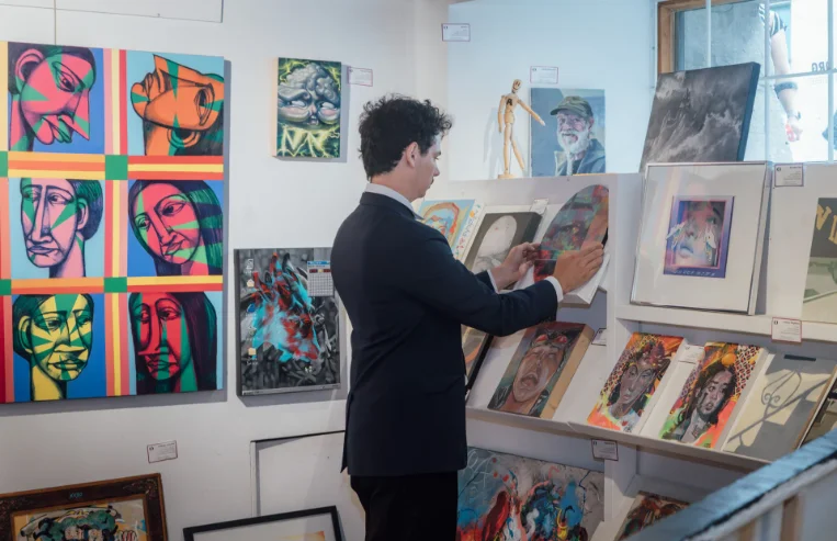 An L'Original advisor in front of a wide selection of paintings in the gallery