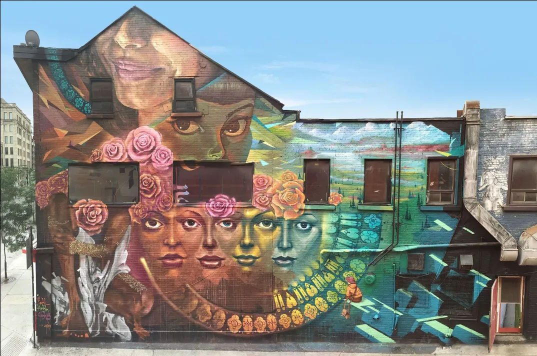 A large mural of faces and roses on the side of a Montreal building